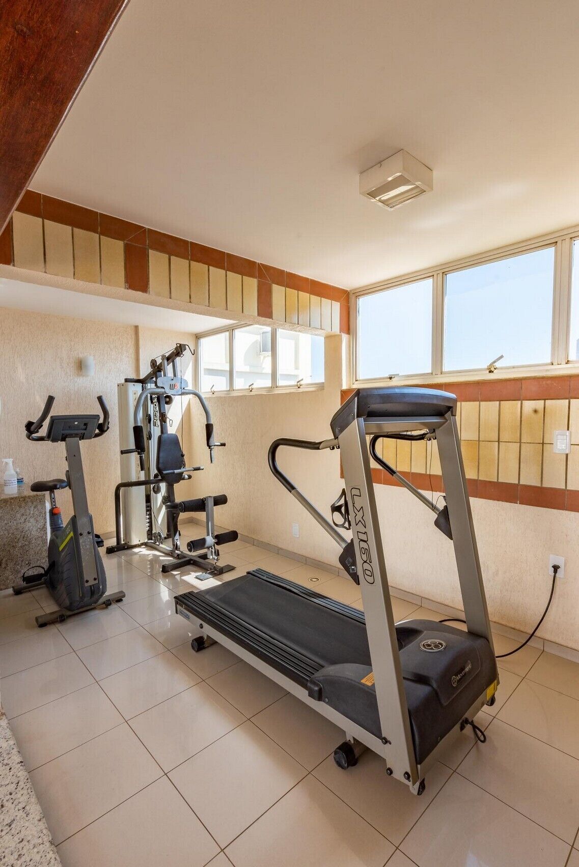 Un gimnasio en casa con cinta de correr, elíptica y máquina de pesas.