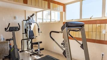 Un gimnasio en casa con cinta de correr, elíptica y máquina de pesas.
