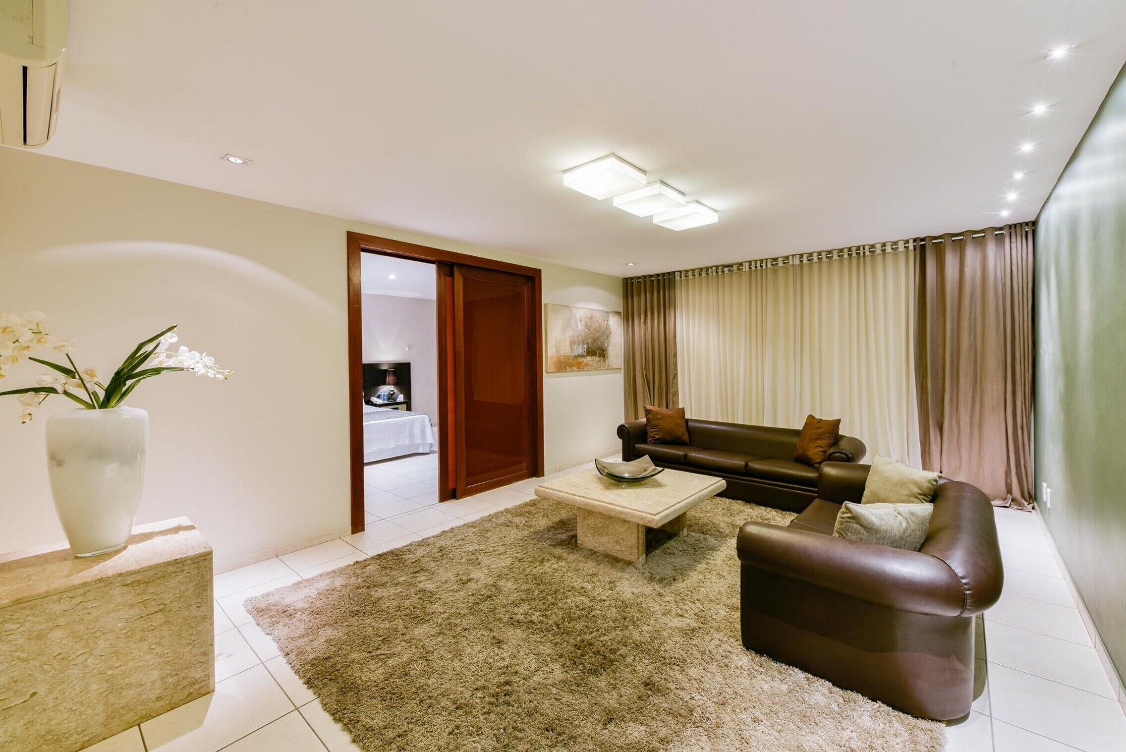 A modern living room with a sofa, coffee table, and a large vase of flowers.