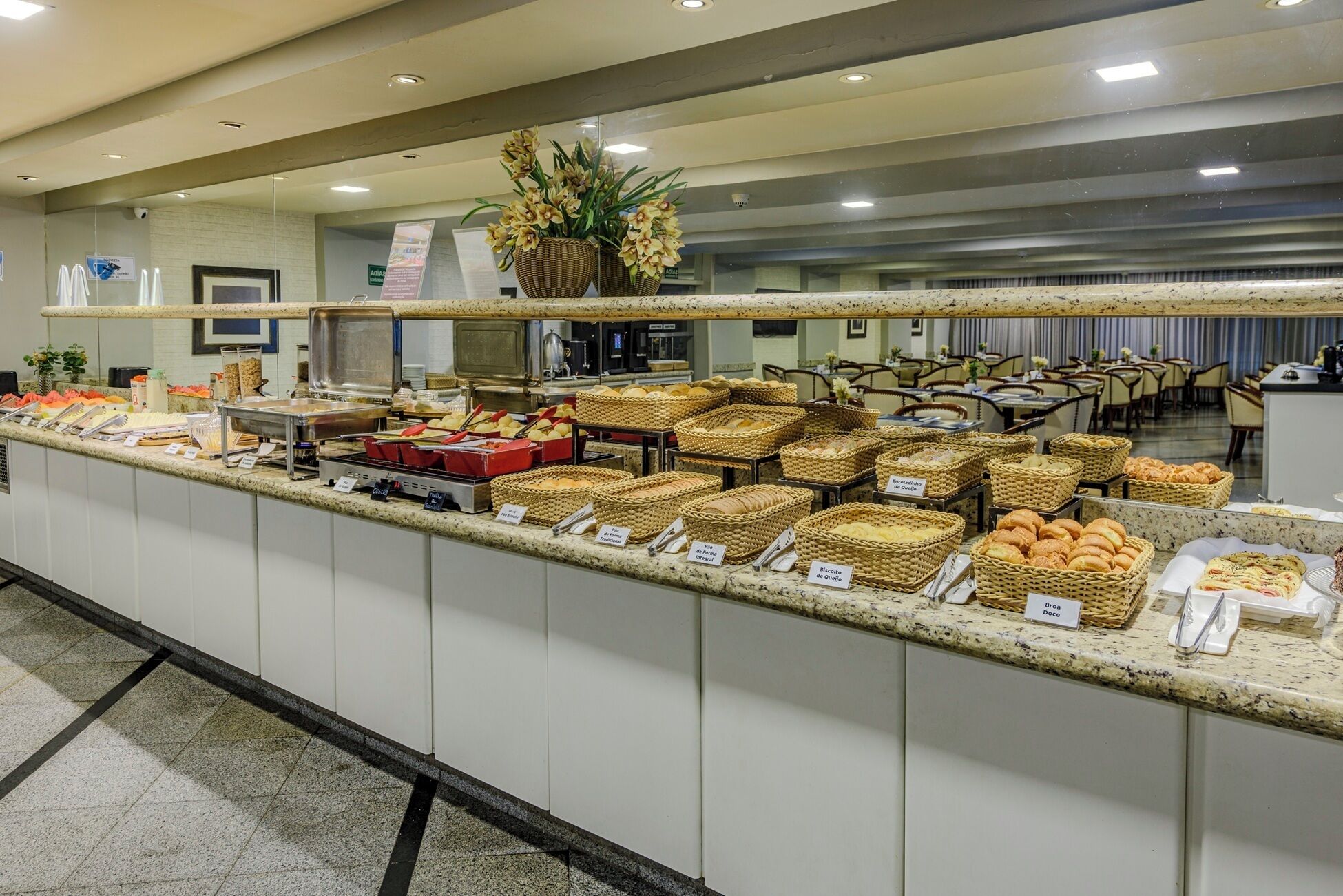 A buffet with various food items and baskets labeled with names like 'Pão de Queijo' and 'Biscoito de Queijo'.