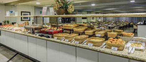 A buffet with various food items and baskets labeled with names like 'Pão de Queijo' and 'Biscoito de Queijo'.