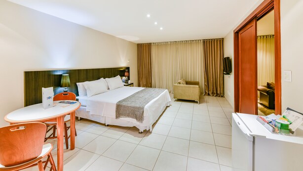 A hotel room with a bed, a desk, a chair, and a small table. - Plaza Inn Augustus - Downtown (Goiania)