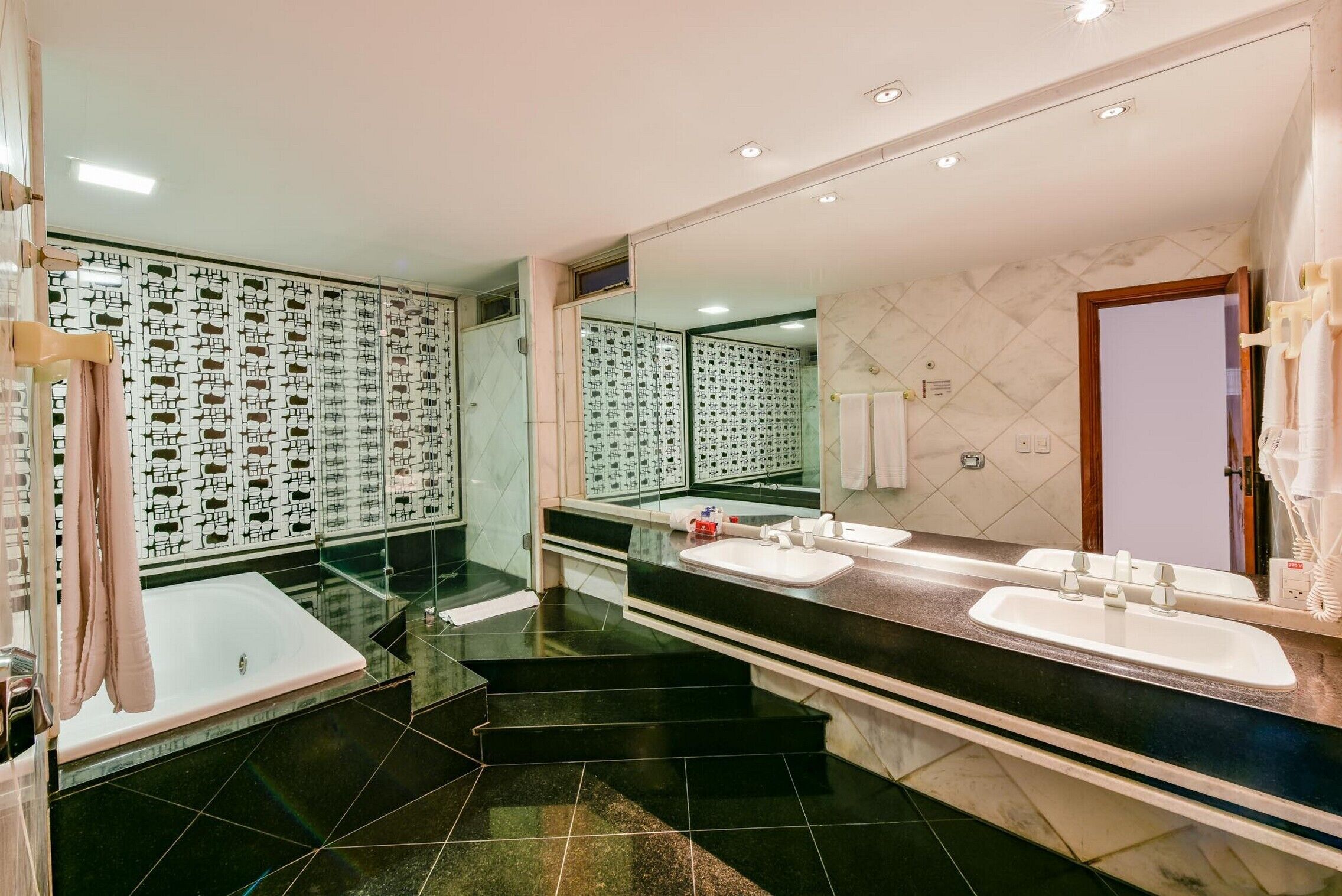 Un baño moderno con un espejo grande, dos lavabos, una bañera y una zona de ducha.