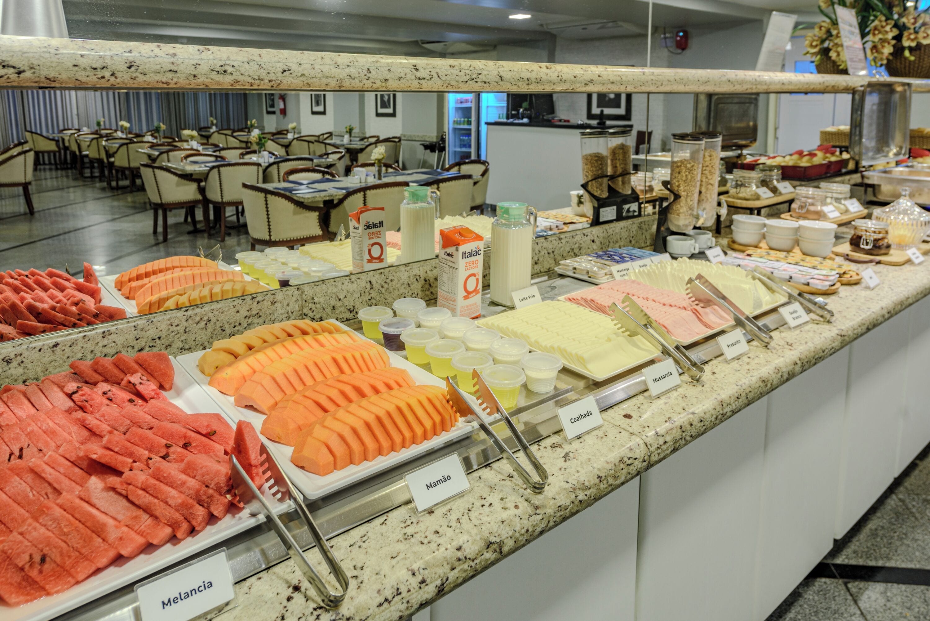 A buffet with various food items and a seating area in the background.