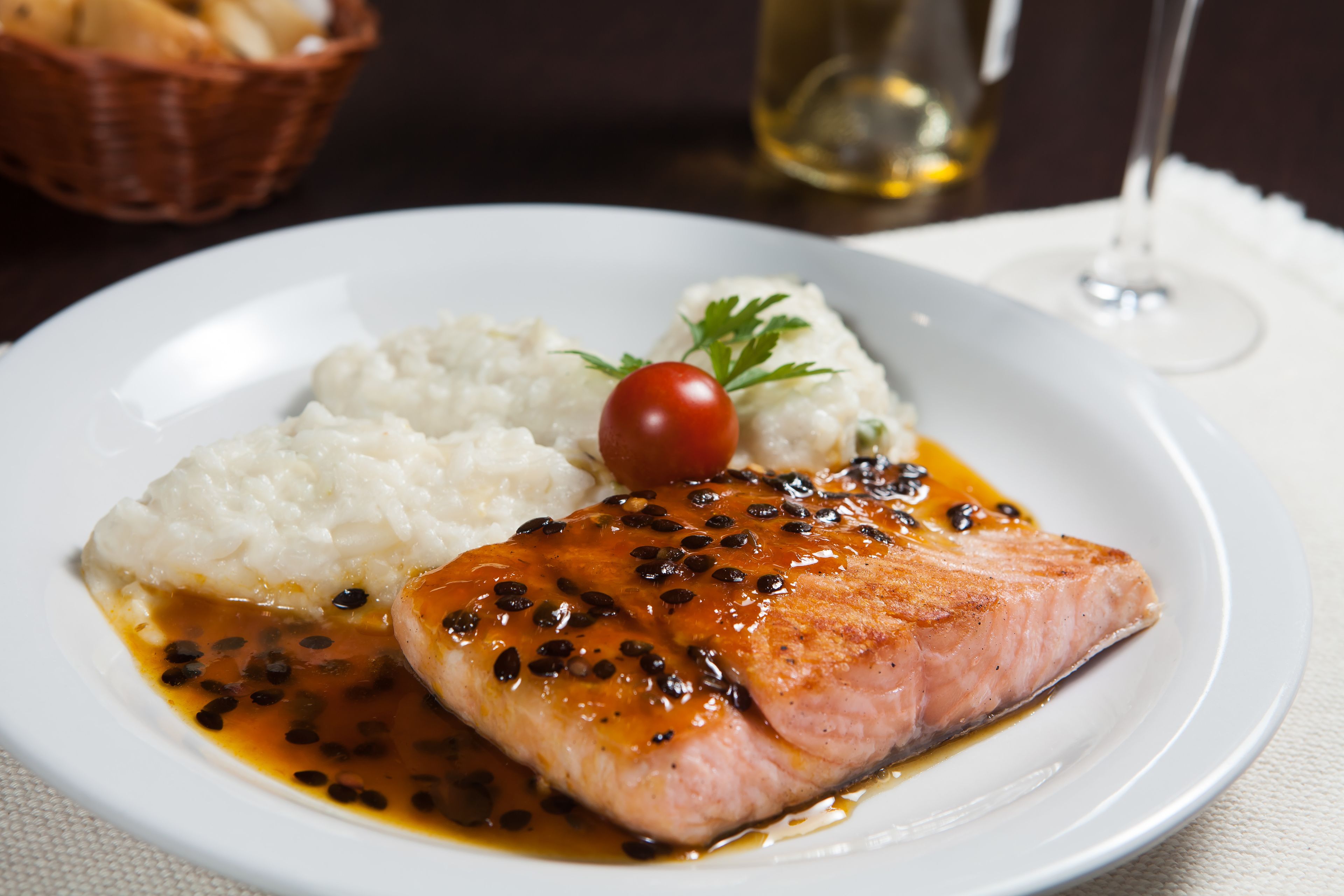 A plate with salmon, mashed potatoes, and a cherry tomato.