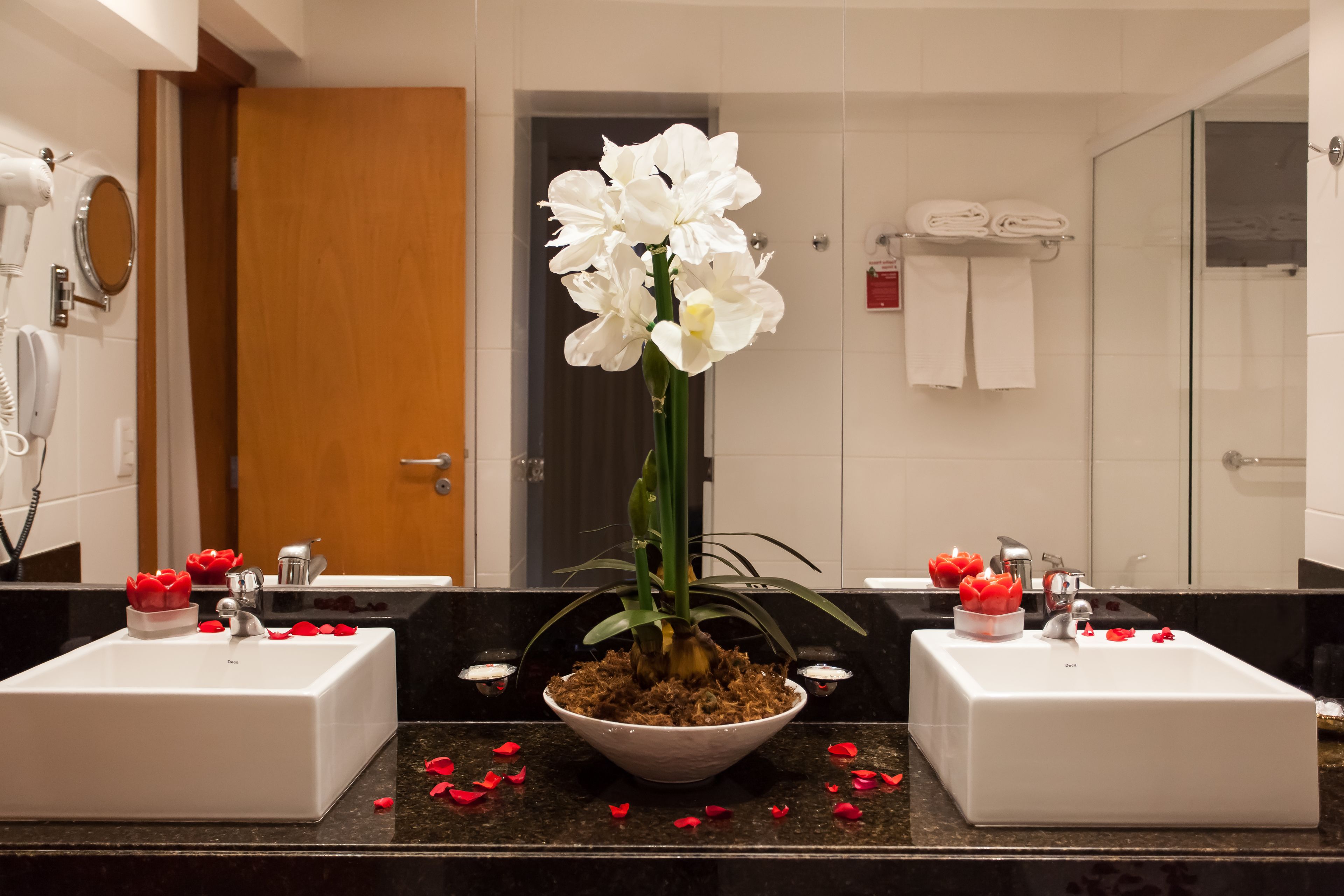 A bathroom with two sinks, a large mirror, and a potted orchid.