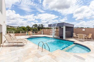 Una piscina al aire libre, sillones reclinables de piscina