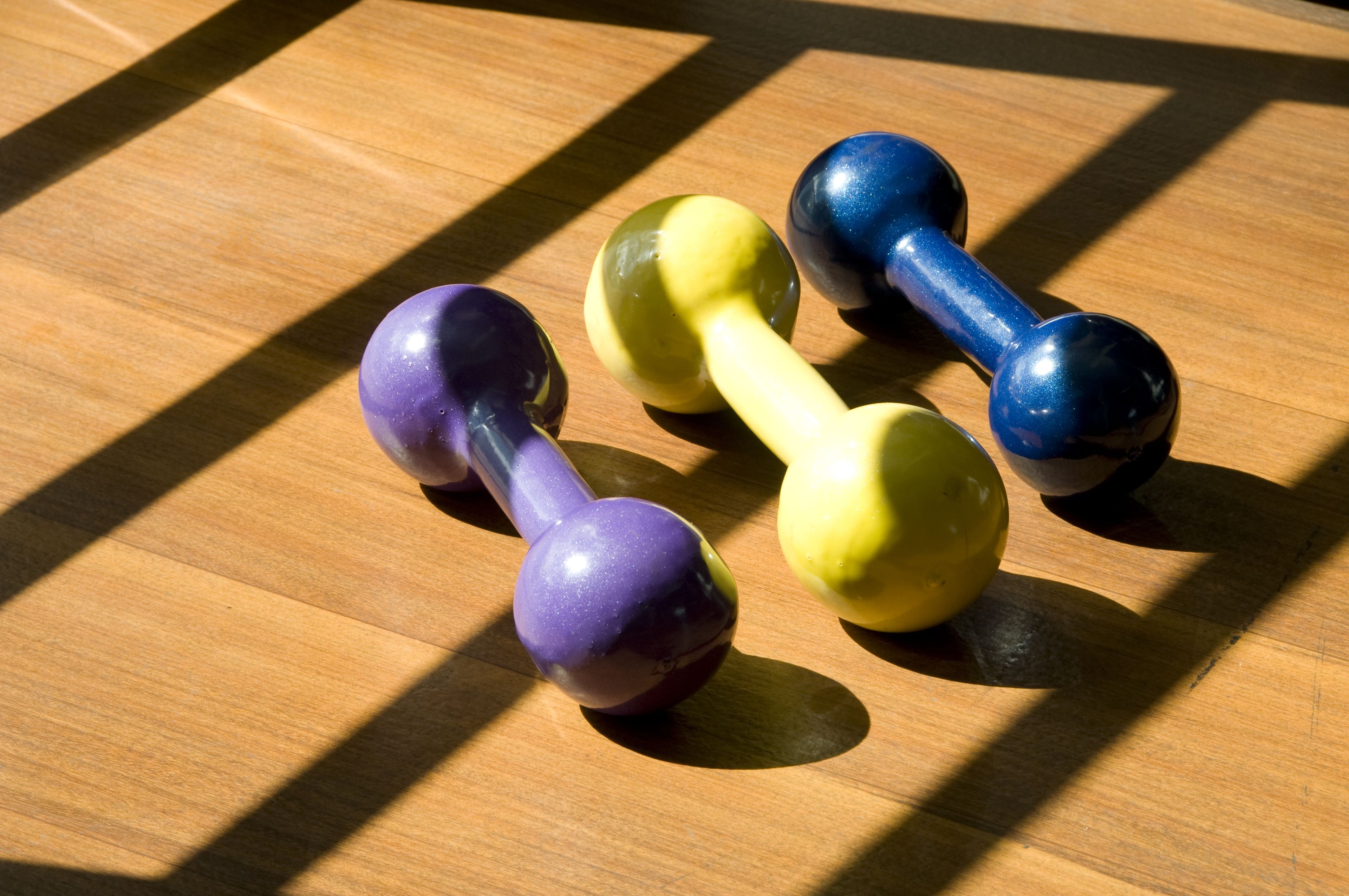 Three dumbbells on a wooden surface.