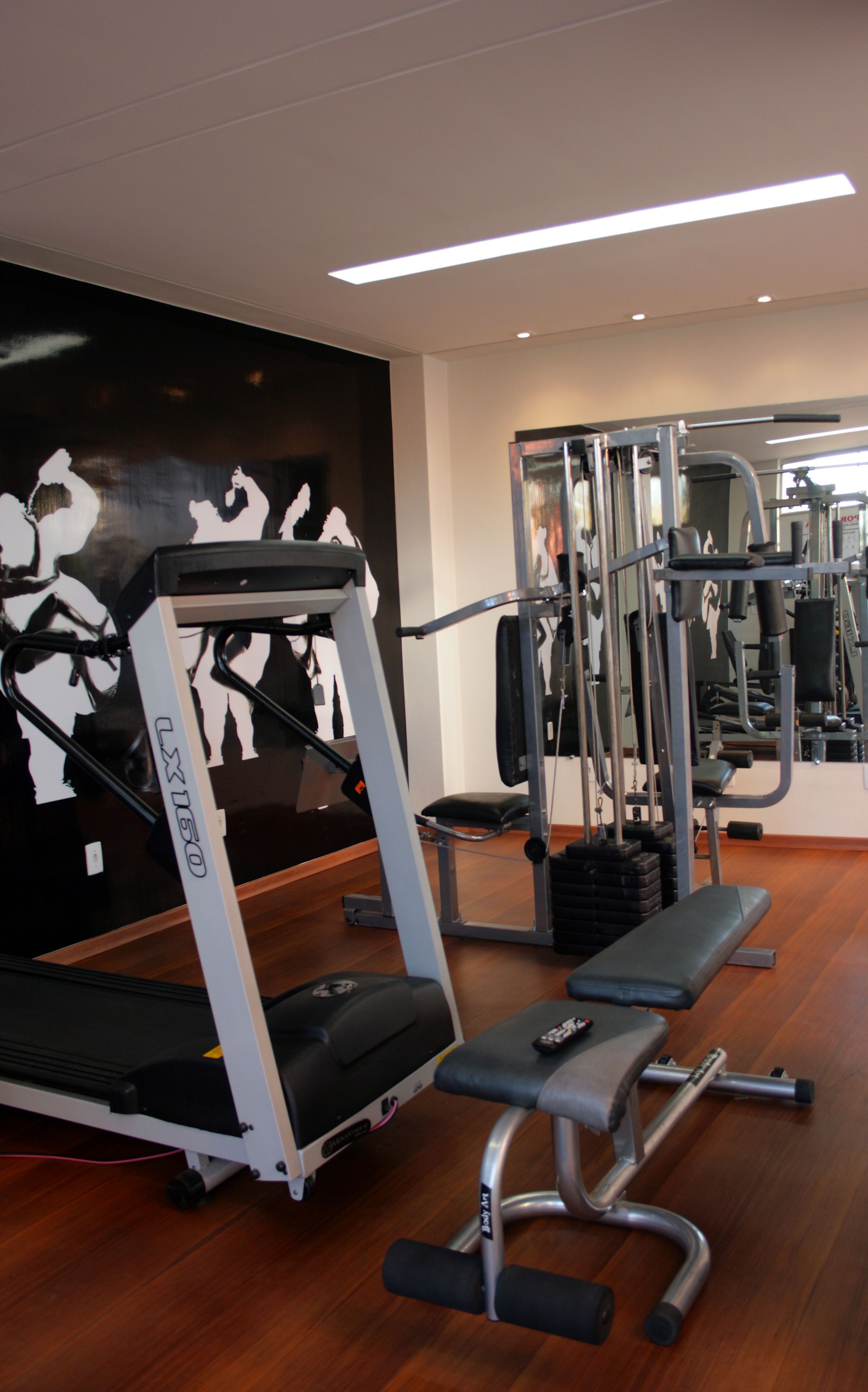 Et fitnesscenter med løbebånd, træningsmaskiner og en bænk.