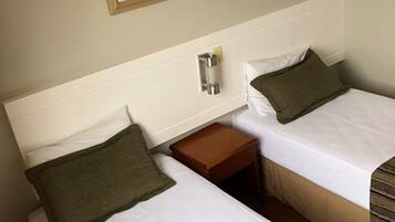 A hotel room with two beds, a framed abstract painting, a bedside table, and a nightstand.