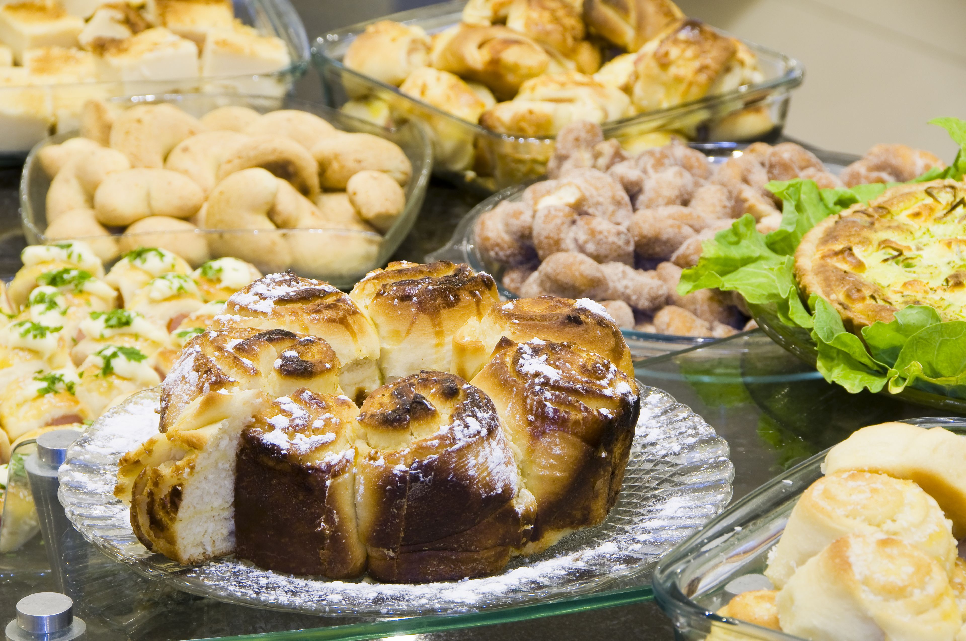 Buffet com diversos produtos de panificação, incluindo pastelaria e pão.