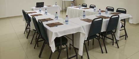 A conference room with tables set for meetings, equipped with laptops, water bottles, and name cards.