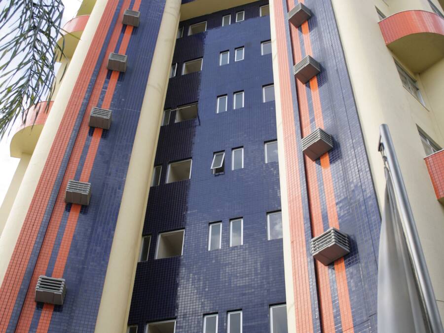 Un edificio de varios pisos con un diseño arquitectónico moderno, que combina colores azul, beige y naranja.