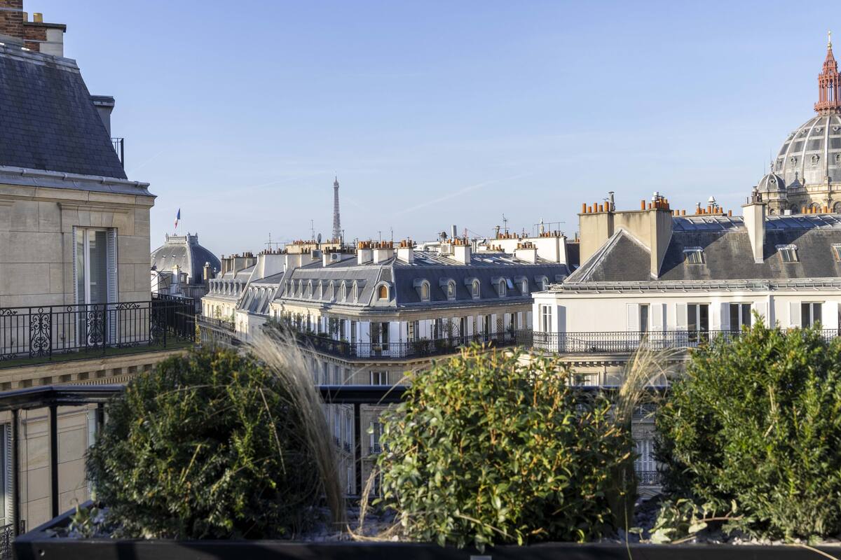 A view of Parisian rooftops with a prominent tower in the background, likely the Eiffel Tower.