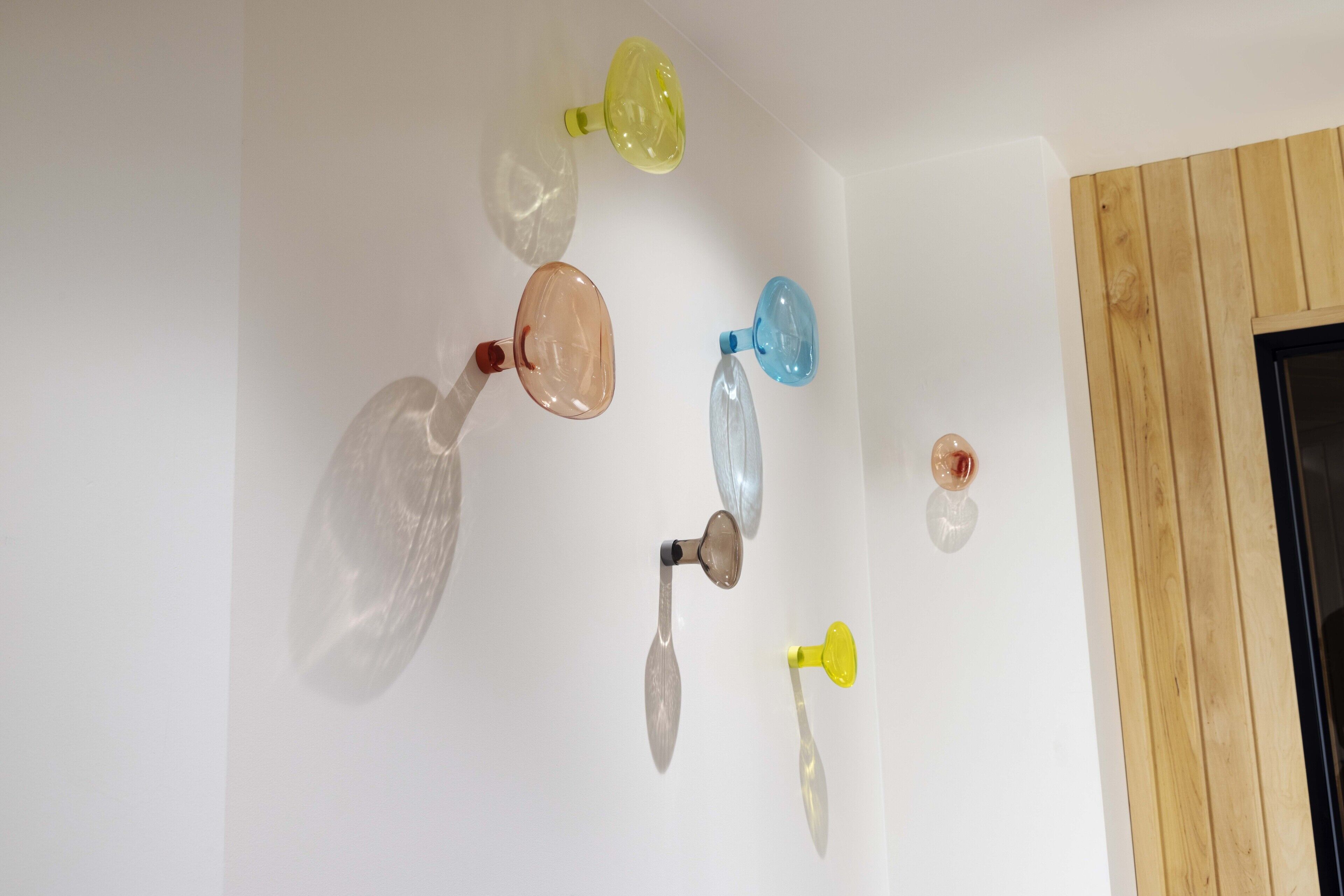 A white wall with several transparent, colorless objects hanging from it.