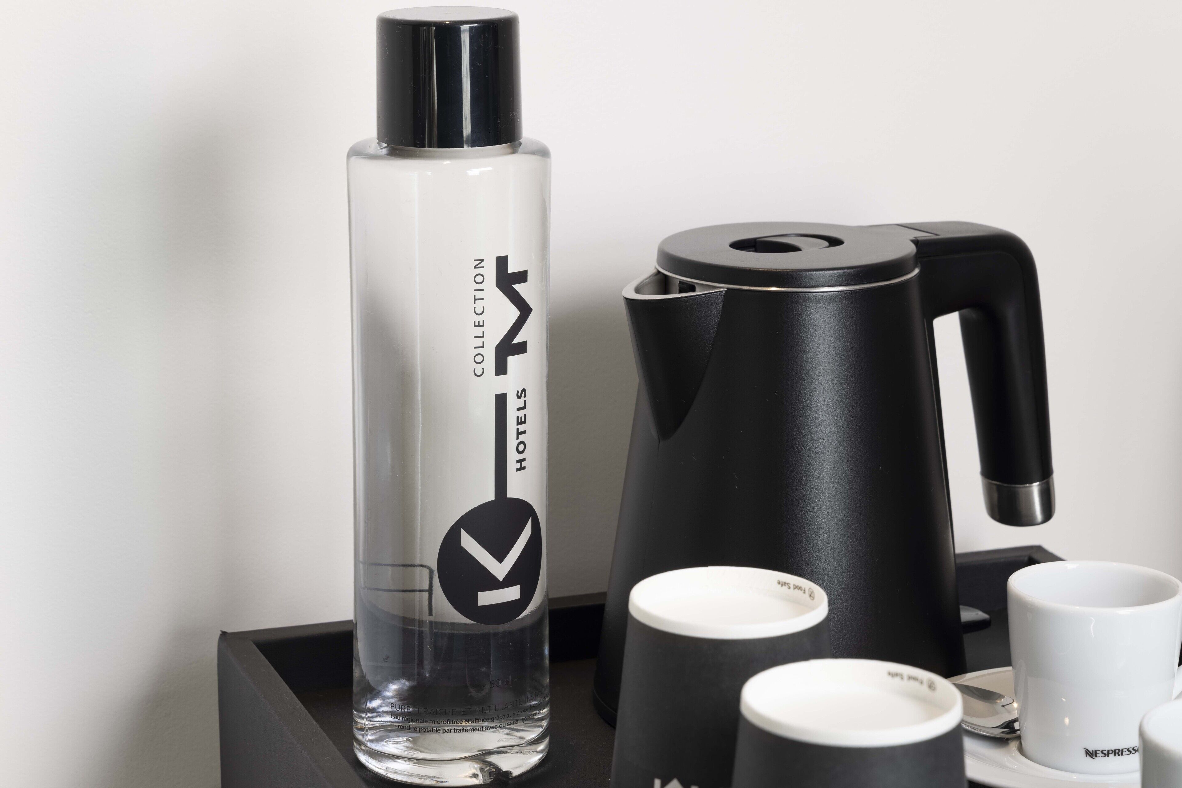 Disposición de un minibar de hotel que incluye una botella de minibar, una cafetera y dos tazas Nespresso.