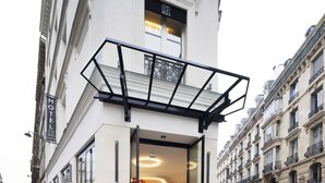 A hotel entrance with a glass door, a balcony with a metal railing, and a sign indicating it is a hotel. - Le 12 Hotel (Paris)