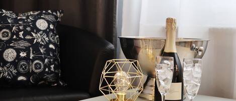 A table with a bottle of Prosecco, two glasses of champagne, and a decorative light fixture.