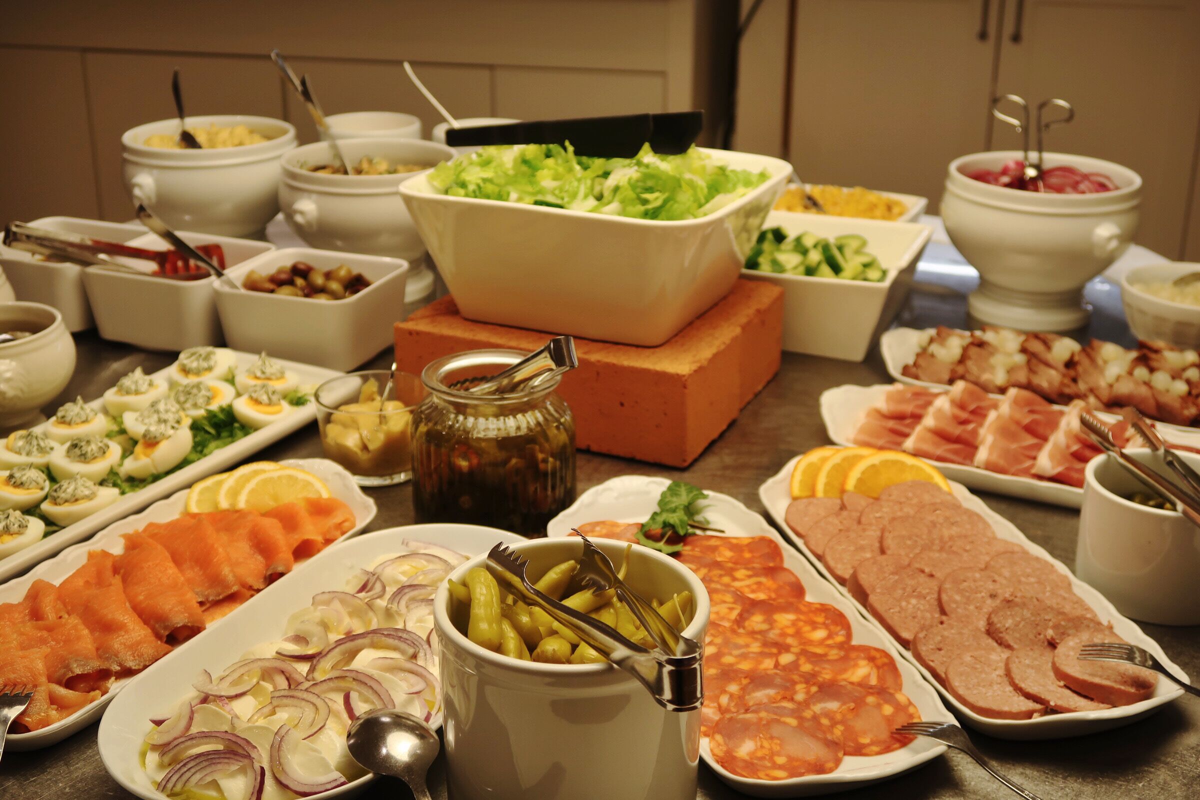Een buffet met diverse gerechten, waaronder zalm, eieren en salades.