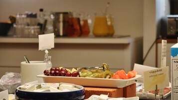 Ein Buffet mit verschiedenen Speisen, darunter Obst, Käse und Sahne.