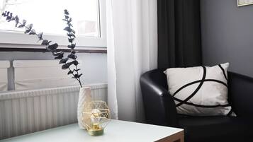 A modern living room with a white table, a black leather chair, and a decorative vase with a geometric design.
