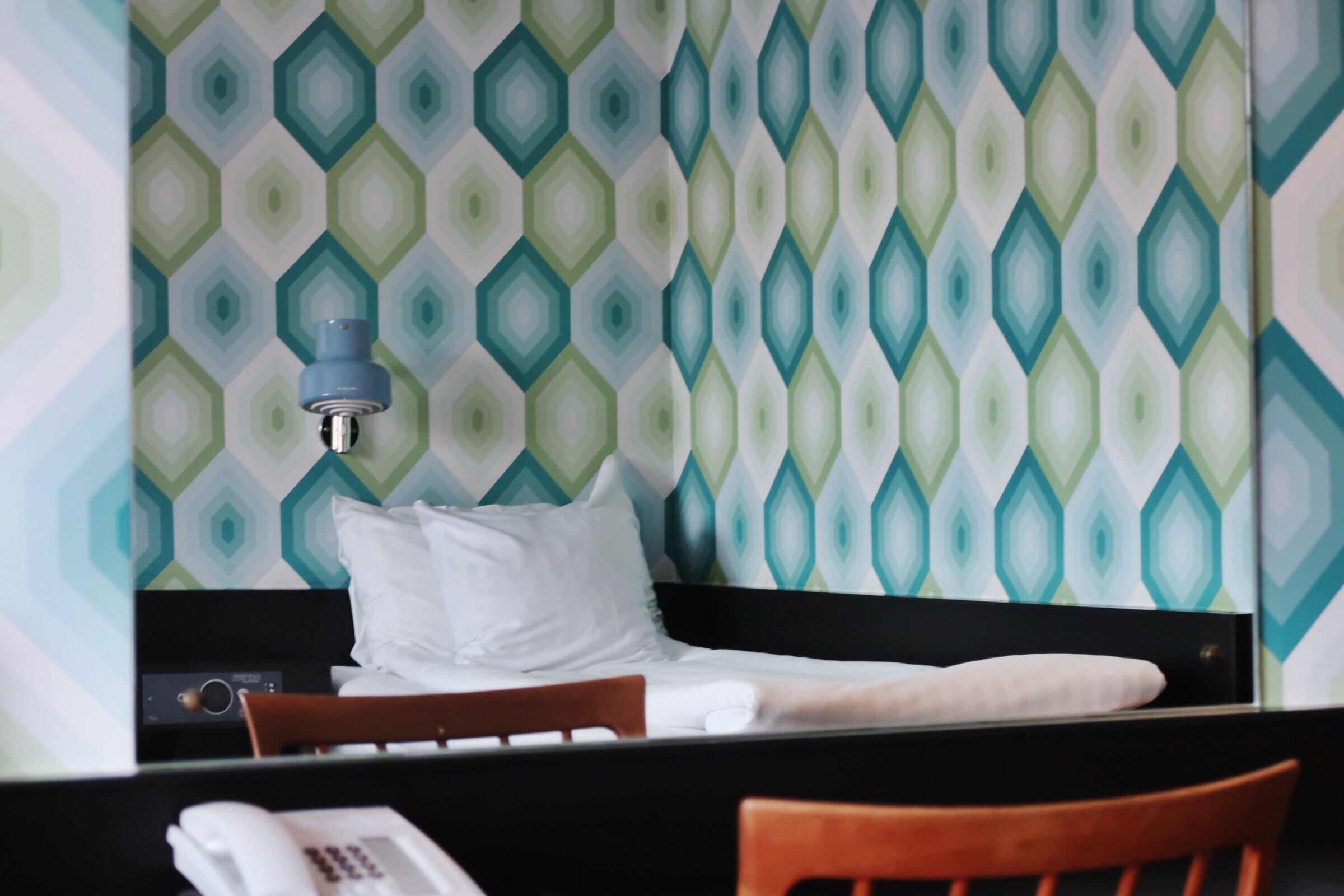 Ein Hotelzimmer mit einem Bett, einem Holzstuhl und einem Telefon.