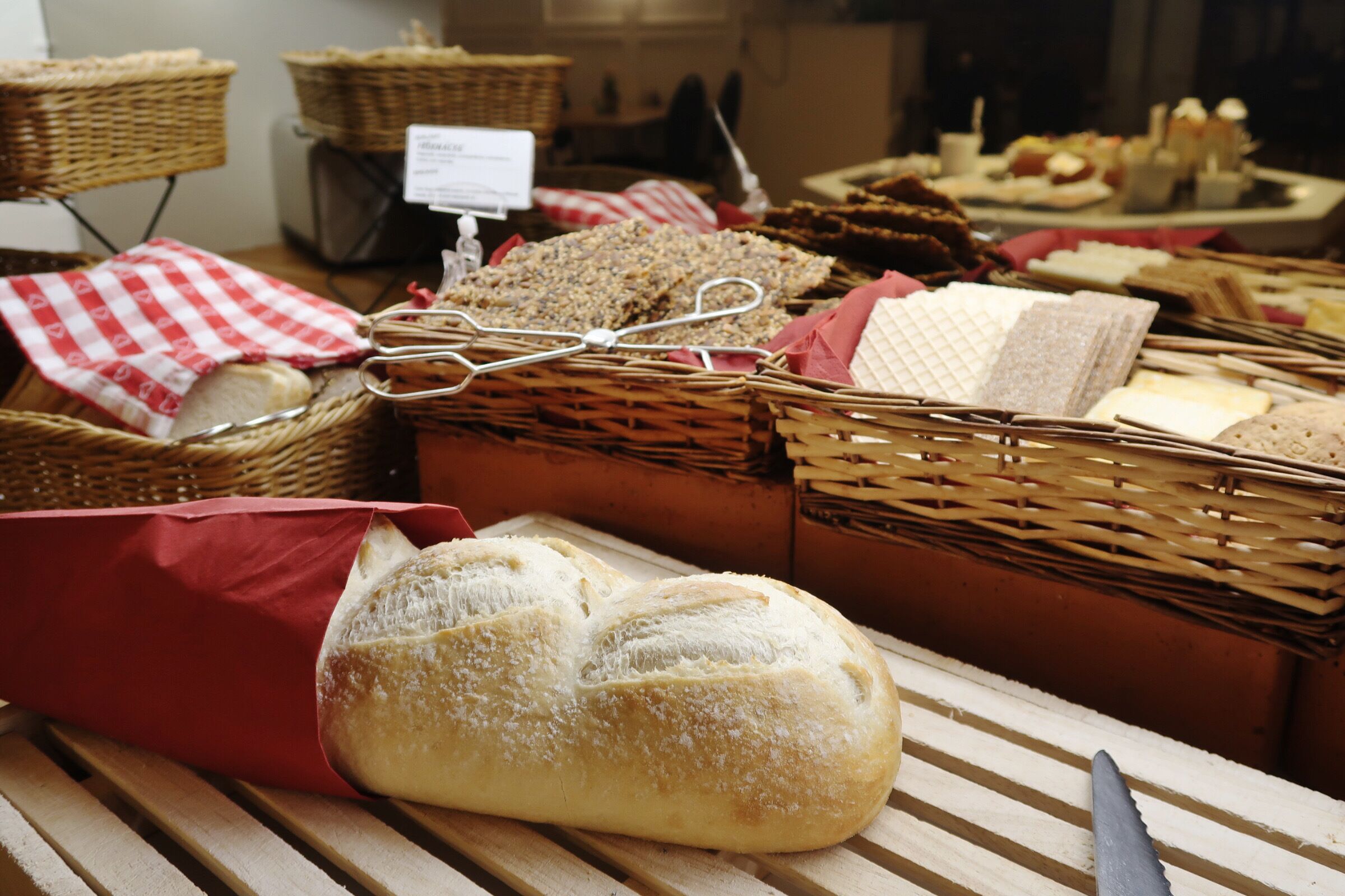 Una variedad de panes y pasteles expuestos sobre una mesa de madera con cestas y telas.