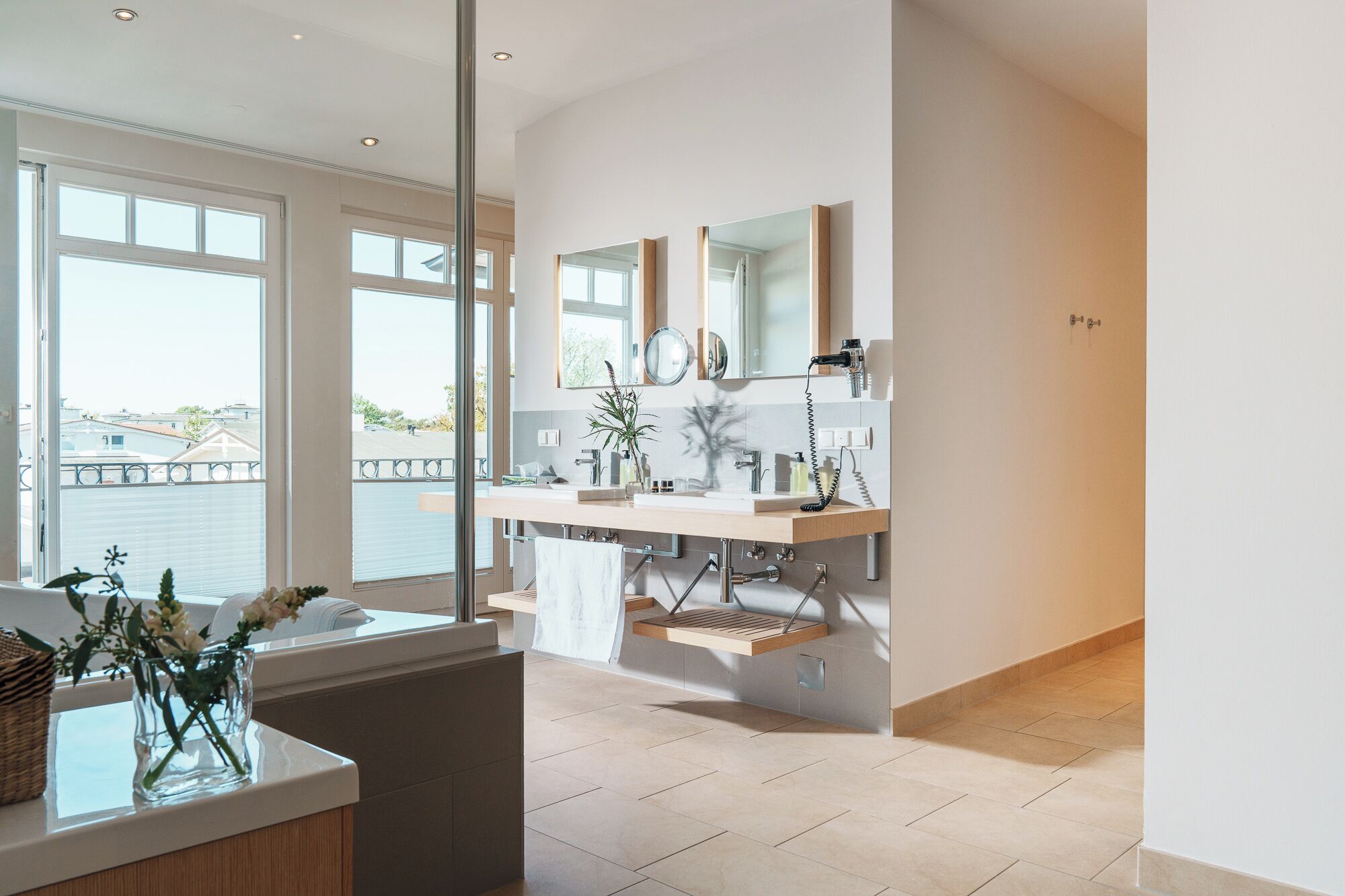 A modern bathroom with a large window, a sink with a mirror, and a towel rack.