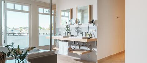 A modern bathroom with a large window, a sink with a mirror, and a towel rack.