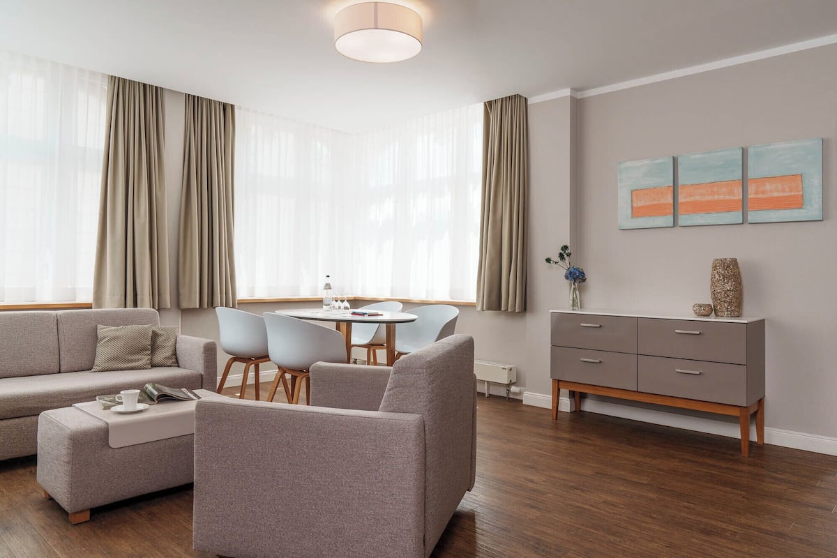 A modern living room with a sofa, chairs, a dining table, and a cabinet.