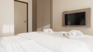 A hotel room with a bed, a wardrobe, and a flat-screen TV mounted on the wall.