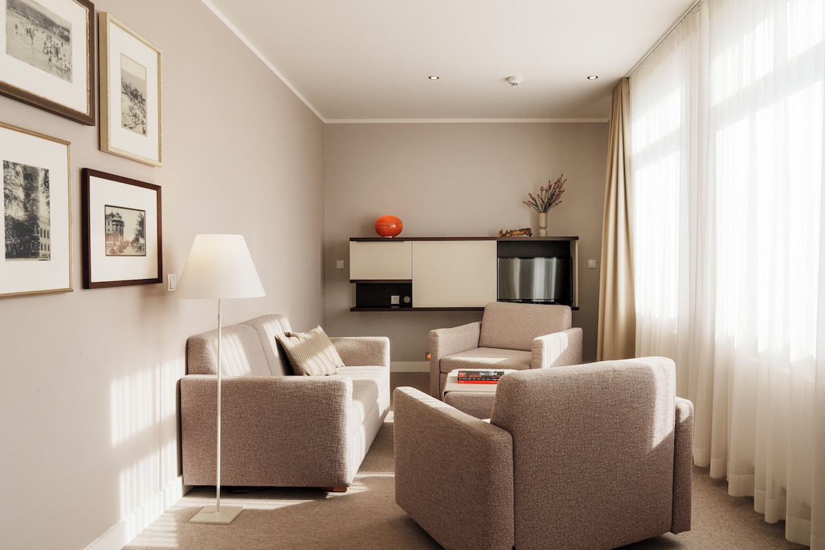 A modern living room with a sofa set, a floor lamp, and a flat-screen TV.