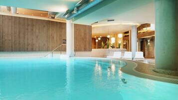 Una piscina interior con pared de madera, sillas de descanso e indicador de profundidad de 1,35 metros.
