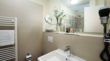 A modern bathroom with a white sink, a towel rack, a mirror, and a hairdryer.