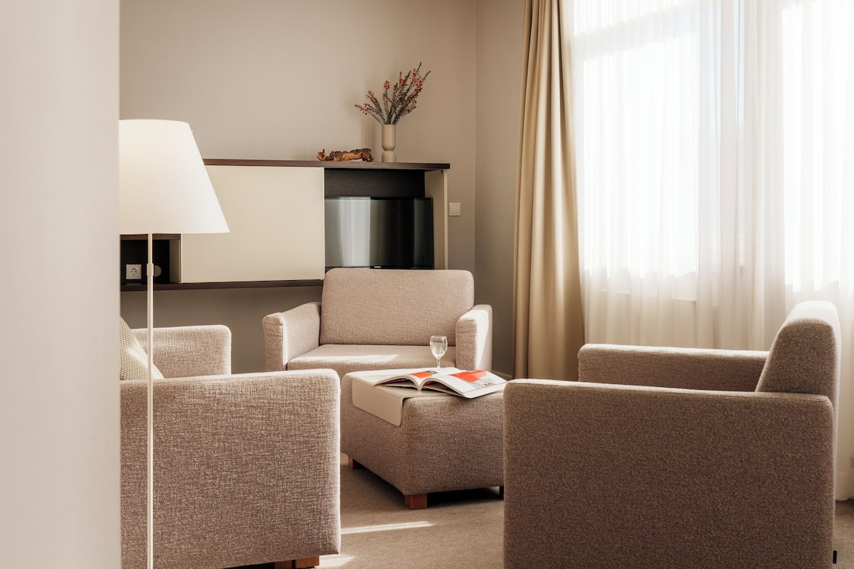A modern living room with a sofa, armchairs, a coffee table, and a lamp.