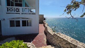 Ein Küstengebäude mit einer Steinmauer und einem roten Weg zum Meer.