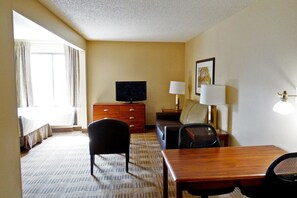 A hotel room with a bed, a desk, a chair, a television, a lamp, and a window with curtains. - Extended Stay America - Houston - Northwest (Houston)
