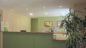 A reception area with a green counter, a door, and a plant. - Extended Stay America - Houston - Northwest (Houston)