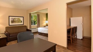 A hotel room with a bed, a desk, a chair, a refrigerator, and a window with curtains. - Extended Stay America - Houston - Northwest (Houston)