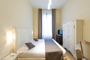 Ein Hotelzimmer mit Bett, Nachttisch, Lampe, Kleiderschrank und Fernseher.