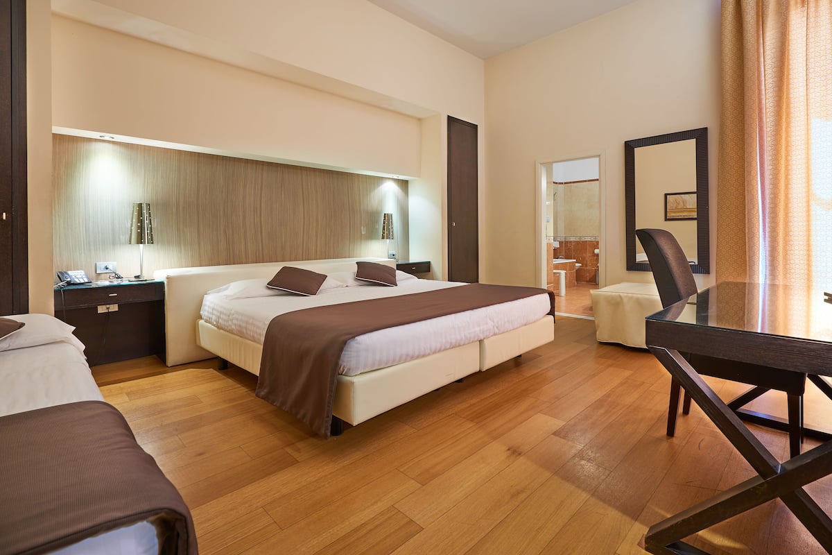 Ein Hotelzimmer mit einem großen Bett, Nachttischen, einem Schreibtisch und einem Stuhl.