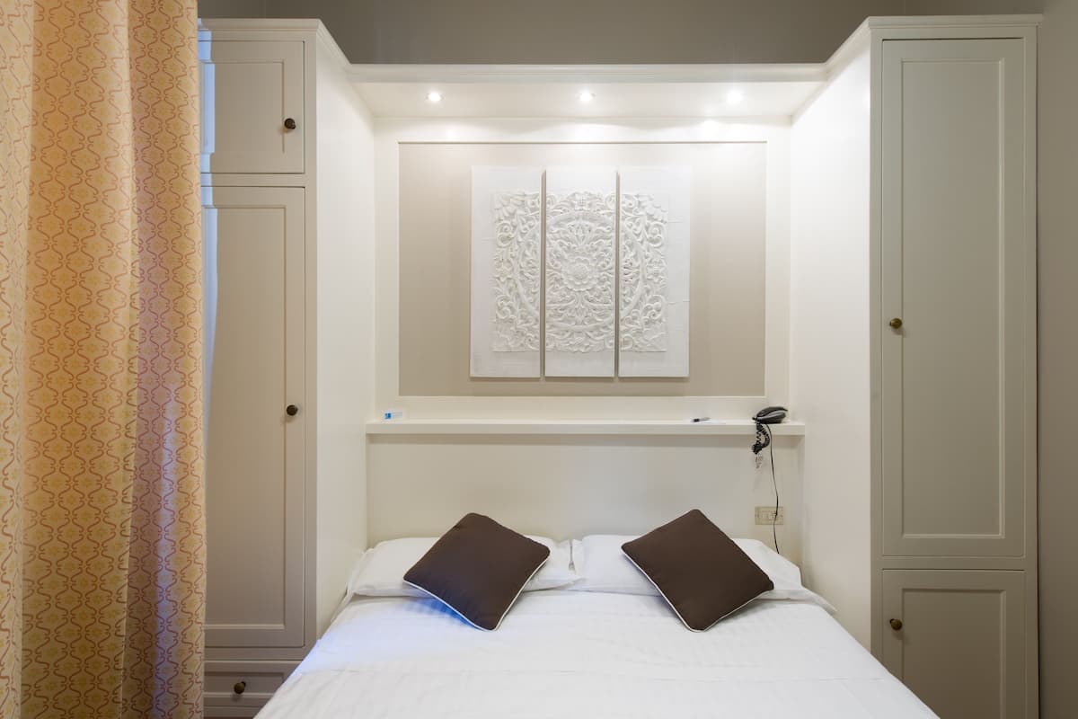 Ein Hotelzimmer mit einem Bett, zwei Kissen, einem Nachttisch, einem Telefon und einer dekorativen Wandverkleidung.