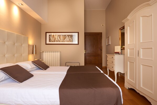 Una habitación de hotel con dos camas, un radiador, una obra de arte enmarcada en la pared y un armario.