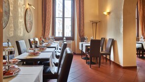A restaurant with multiple tables and chairs, a large window with curtains, and wall-mounted light fixtures. - Hotel Cosimo De' Medici (Florence)