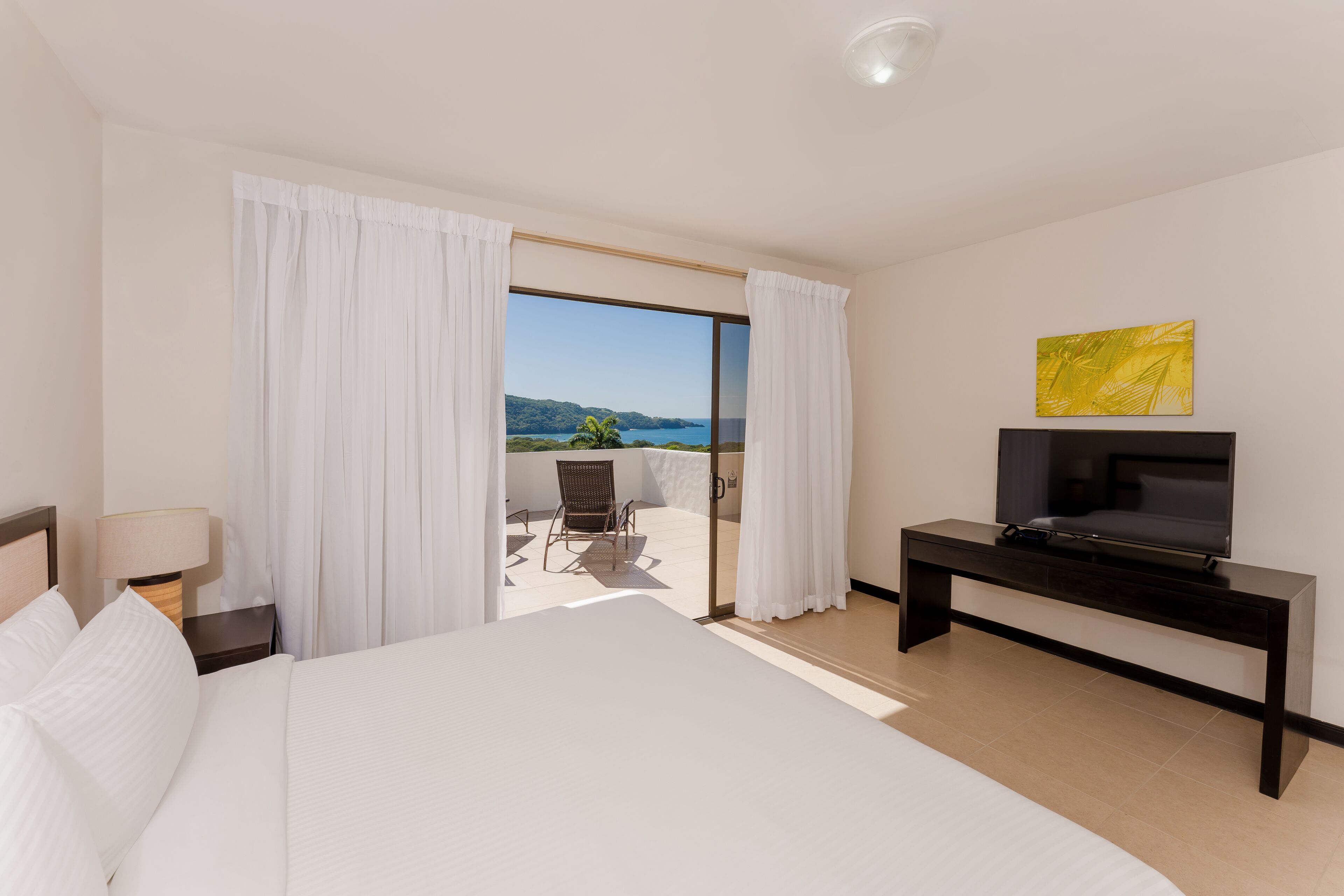 Une chambre d’hôtel avec un lit, un téléviseur posé sur un meuble, un bureau et une vue sur l’extérieur.
