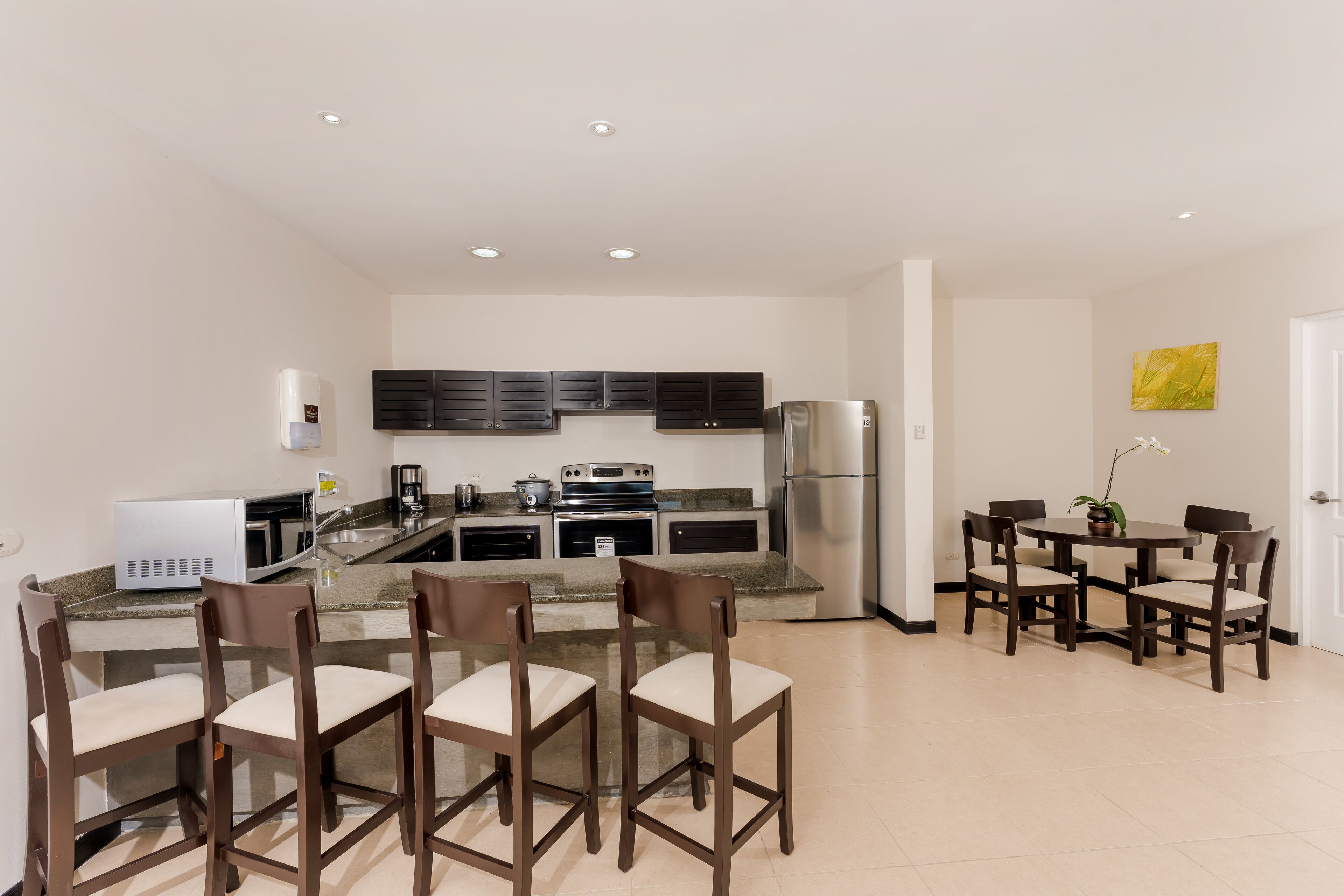 A modern kitchen with a central island, built-in appliances, and a dining area with four chairs.