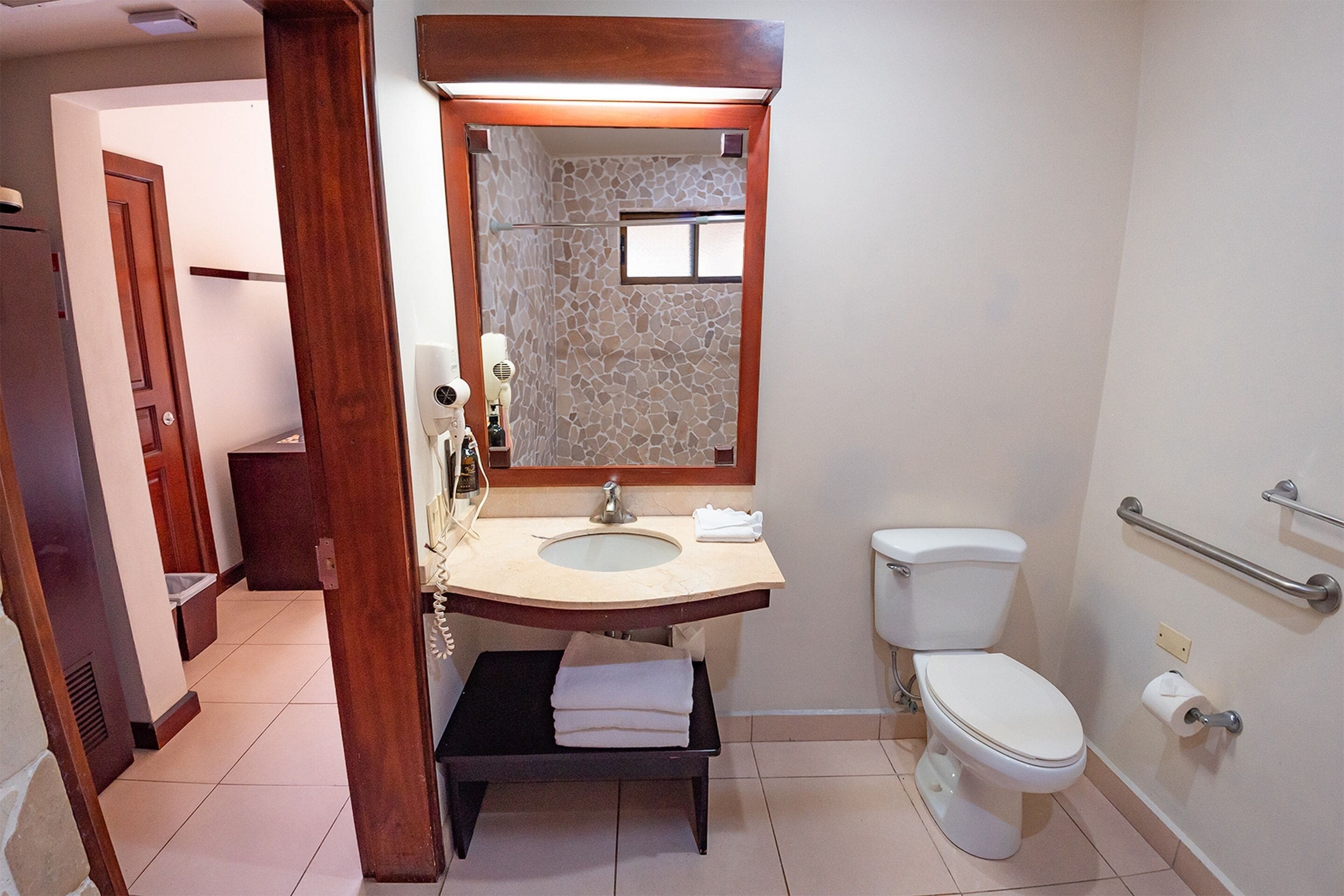 Een badkamer met een wastafel, spiegel, toilet en handdoekhouder.