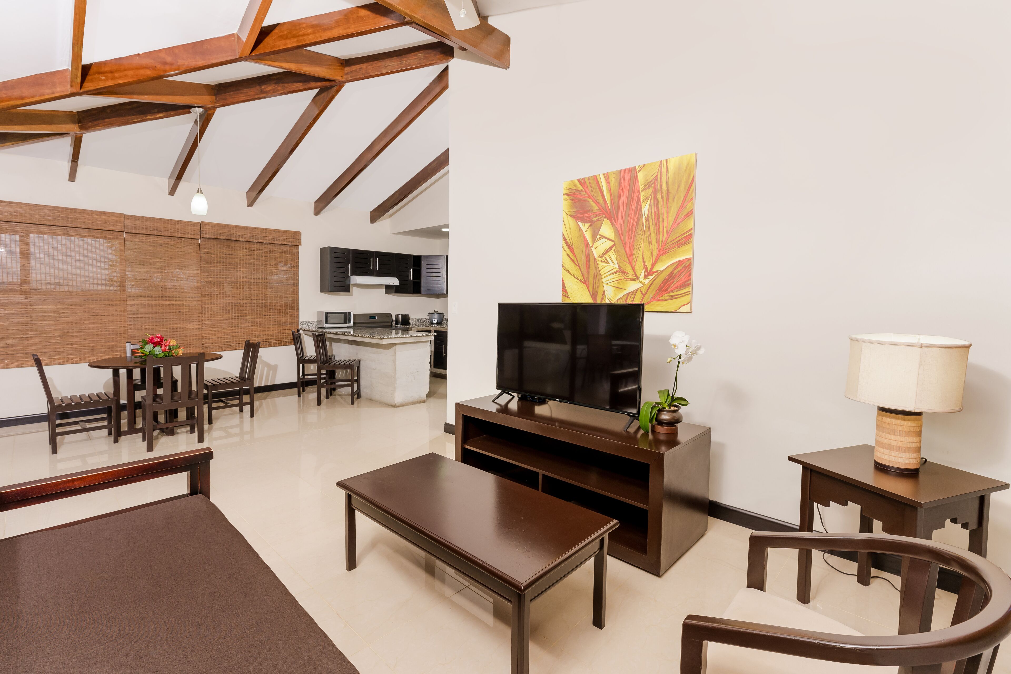 A modern living room with a wooden coffee table, a TV stand, and a dining area with chairs and a table.