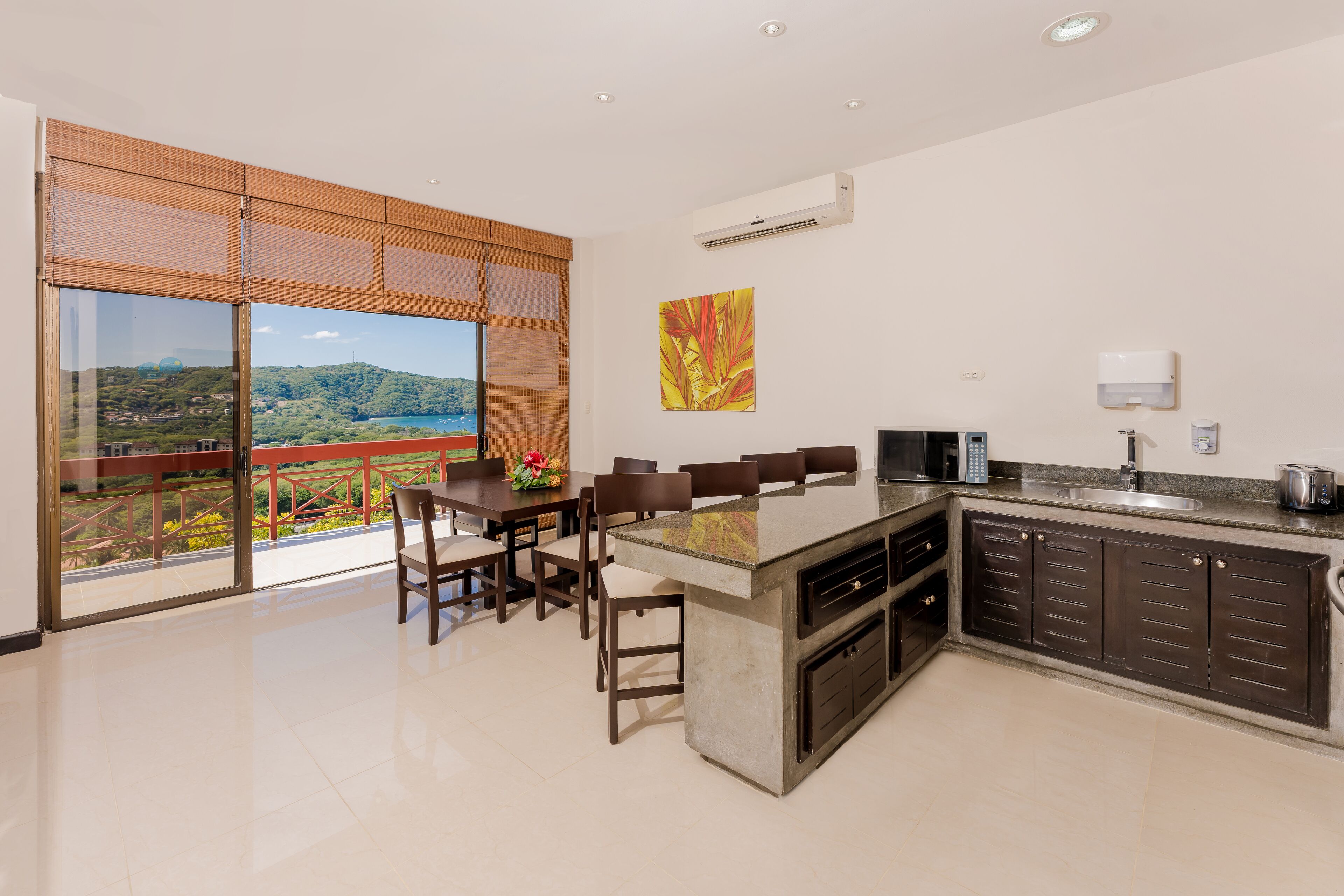 Una cocina moderna con una isla grande, comedor y vistas a un paisaje montañoso.