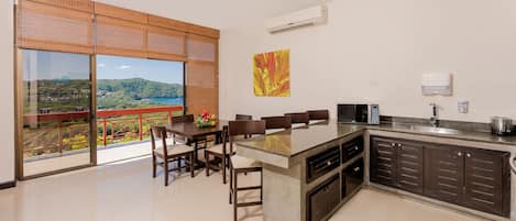 Una cocina moderna con una isla grande, comedor y vistas a un paisaje montañoso.